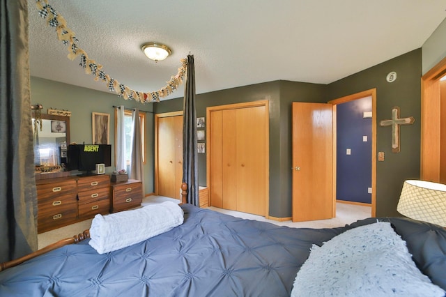 bedroom with multiple closets, light colored carpet, and a textured ceiling