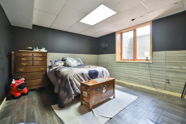 bedroom featuring a drop ceiling and dark wood-type flooring