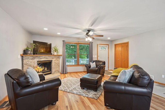 living room with a brick fireplace, ceiling fan, and light hardwood / wood-style floors