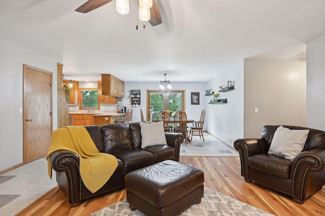 living room featuring light hardwood / wood-style flooring, sink, and ceiling fan with notable chandelier