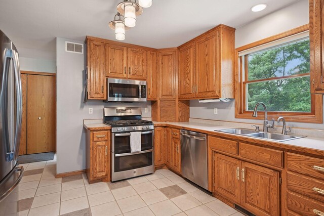 kitchen featuring stainless steel appliances, sink, and light tile patterned floors