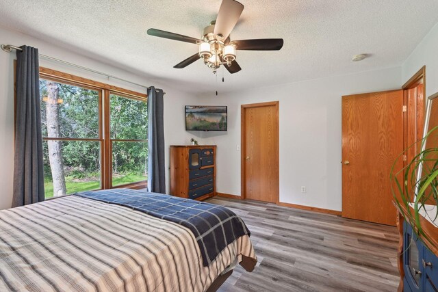 bedroom with a textured ceiling, ceiling fan, and light hardwood / wood-style floors