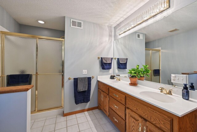 bathroom with tile patterned floors, an enclosed shower, a textured ceiling, and vanity