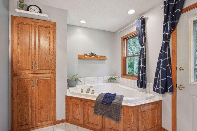 bathroom featuring a tub to relax in, tile patterned flooring, and a textured ceiling