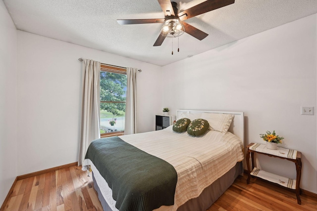 bedroom featuring a textured ceiling, wood-type flooring, and ceiling fan