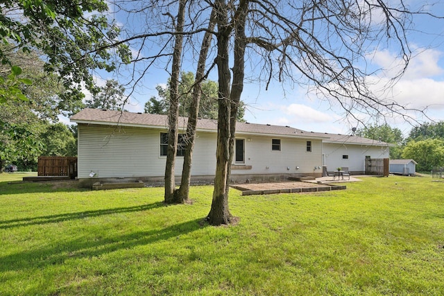 back of property with a fire pit, a patio area, and a lawn