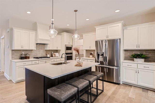 kitchen with stainless steel appliances, white cabinetry, a kitchen island with sink, and pendant lighting