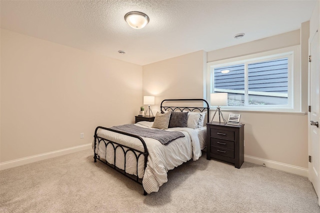 bedroom with a textured ceiling and light carpet