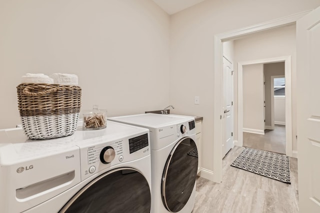 clothes washing area with washer and clothes dryer and light hardwood / wood-style flooring