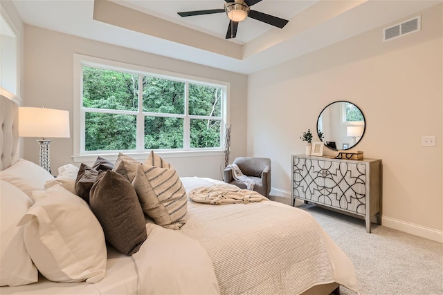 bedroom featuring carpet floors, a tray ceiling, and ceiling fan