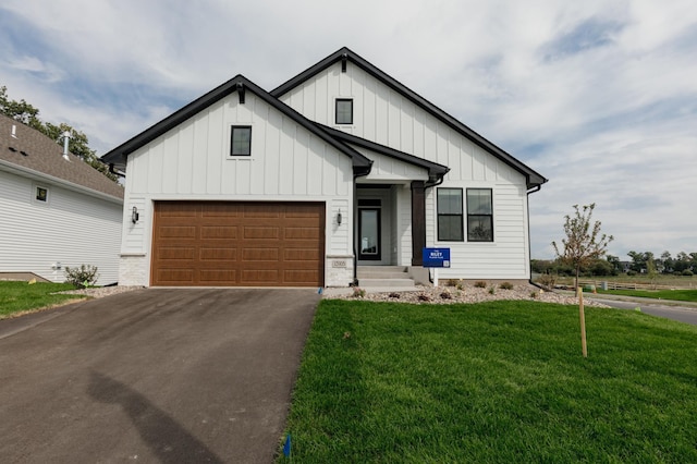 modern farmhouse featuring a garage, a front lawn, board and batten siding, and aphalt driveway