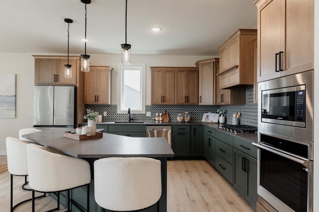 kitchen with a breakfast bar area, stainless steel appliances, a sink, tasteful backsplash, and dark countertops