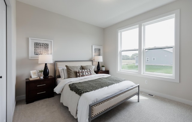 bedroom with baseboards, visible vents, and light colored carpet