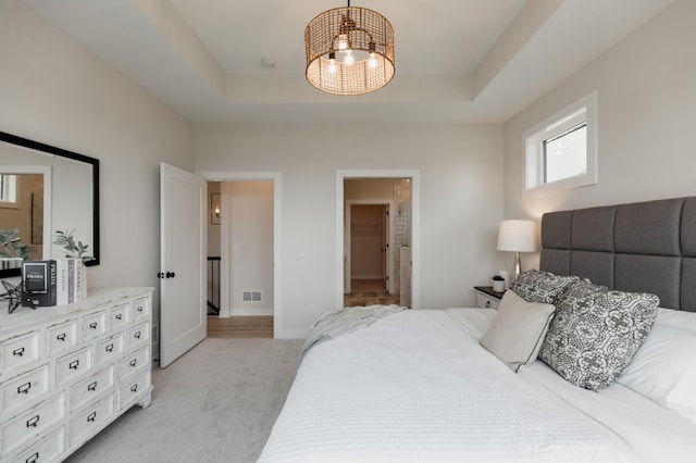 bedroom featuring light colored carpet, a tray ceiling, visible vents, and baseboards