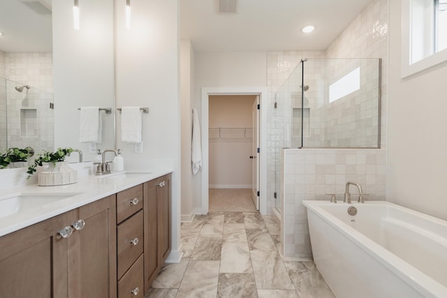 bathroom with a walk in closet, visible vents, a stall shower, a sink, and a freestanding tub