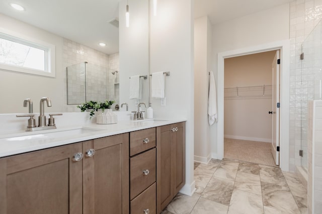 bathroom with double vanity, a sink, a shower stall, and a spacious closet