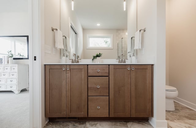 full bathroom featuring toilet, a tile shower, a sink, and double vanity