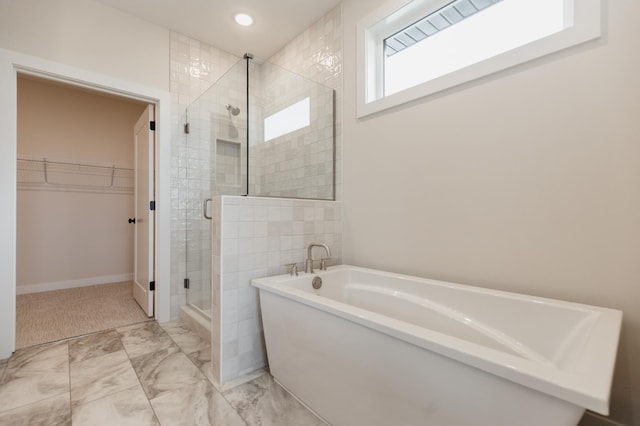 full bathroom featuring recessed lighting, marble finish floor, a soaking tub, a stall shower, and a walk in closet