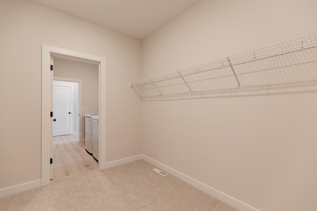 spacious closet featuring washer and clothes dryer and light colored carpet