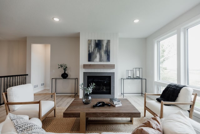 living area featuring recessed lighting, a large fireplace, visible vents, baseboards, and light wood-type flooring