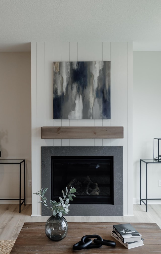 interior details featuring a textured ceiling, a fireplace, and wood finished floors