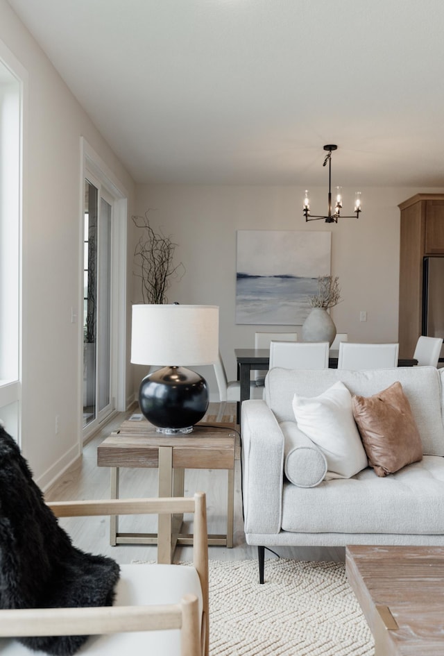 bedroom featuring baseboards, light wood-style floors, multiple windows, and an inviting chandelier