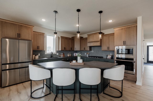 kitchen with stainless steel appliances, a breakfast bar, a kitchen island, backsplash, and dark countertops