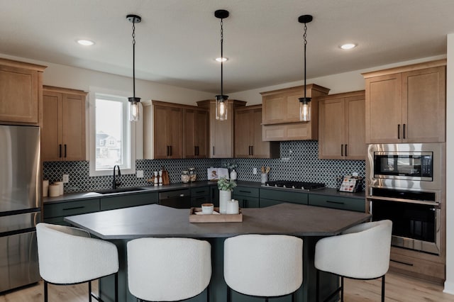 kitchen featuring appliances with stainless steel finishes, dark countertops, a sink, and a kitchen bar