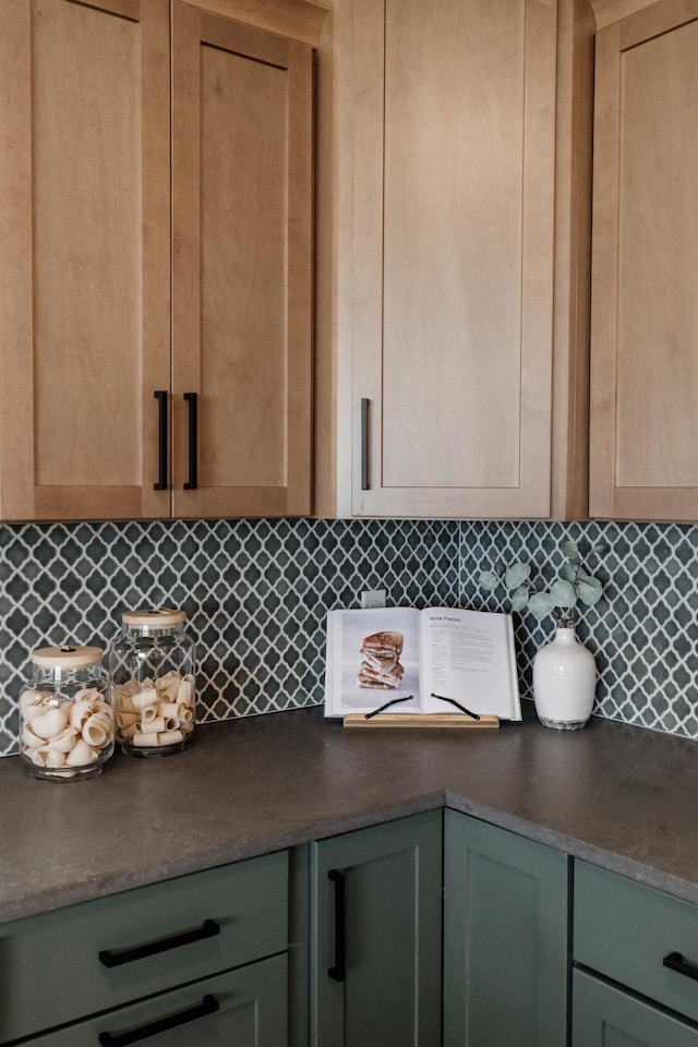 room details with dark countertops, decorative backsplash, and light brown cabinetry