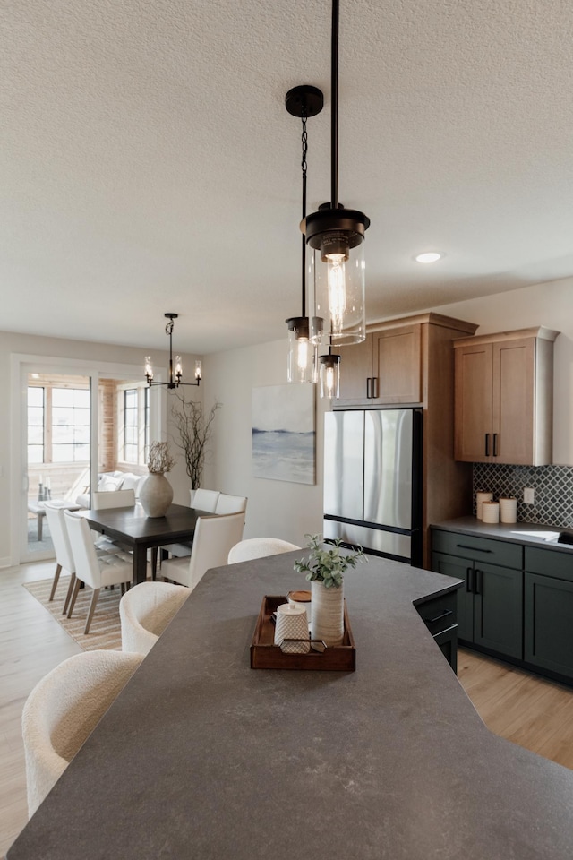 dining area featuring light wood-type flooring, a chandelier, a textured ceiling, and recessed lighting