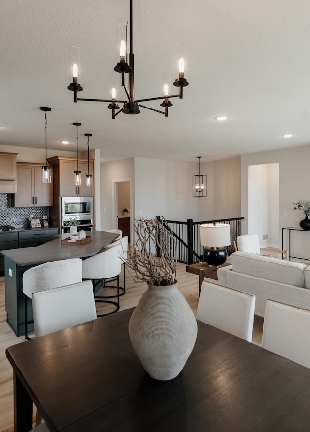 dining space featuring a notable chandelier, a textured ceiling, and light wood finished floors