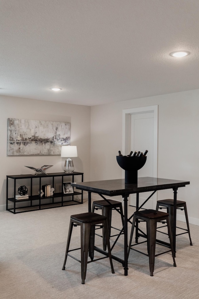 dining area featuring carpet floors, baseboards, and a textured ceiling