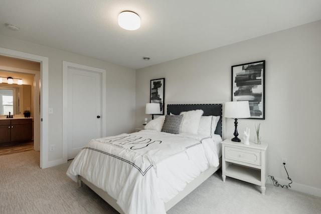 bedroom featuring baseboards, a sink, and light colored carpet