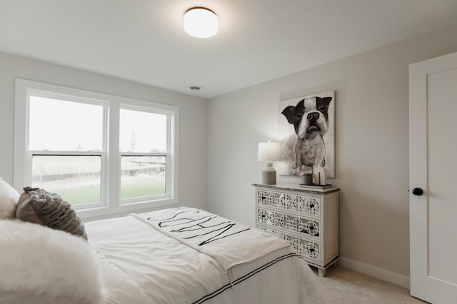 bedroom with baseboards and light colored carpet