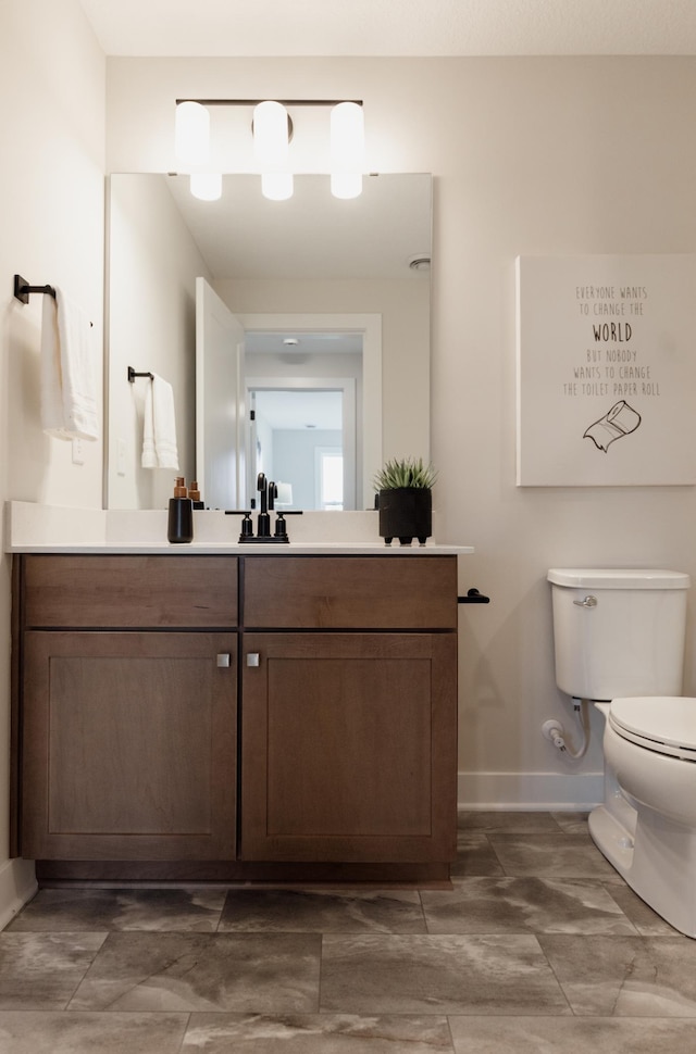 bathroom featuring baseboards, vanity, and toilet