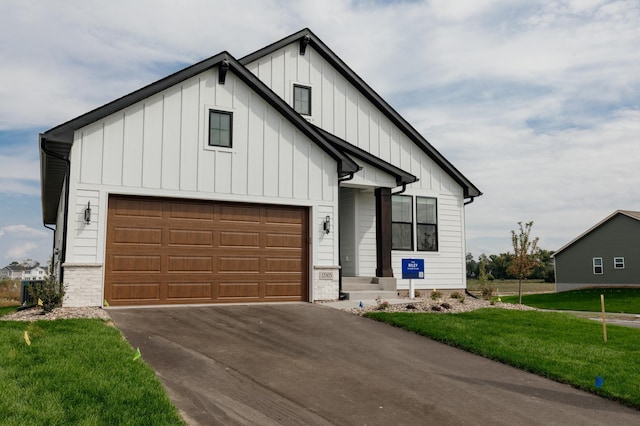 modern inspired farmhouse featuring a garage, driveway, a front lawn, and board and batten siding