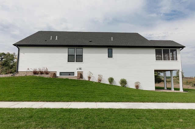 back of house featuring a shingled roof and a lawn