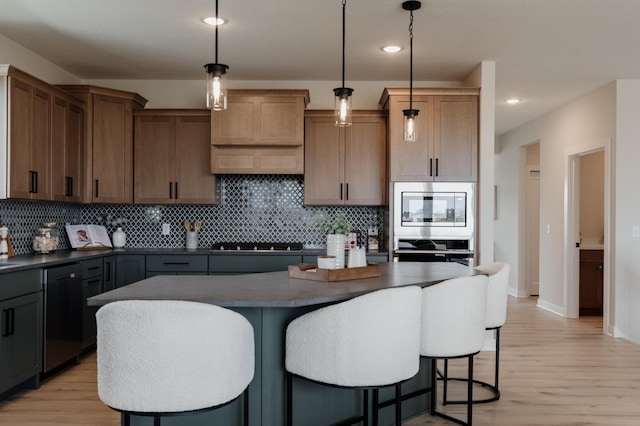 kitchen with a kitchen bar, light wood-type flooring, appliances with stainless steel finishes, dark countertops, and backsplash