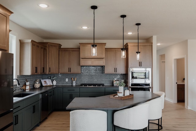 kitchen featuring tasteful backsplash, a sink, dark countertops, black appliances, and light wood-style flooring