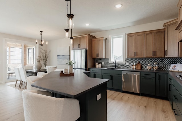 kitchen featuring dark countertops, decorative backsplash, appliances with stainless steel finishes, and a chandelier