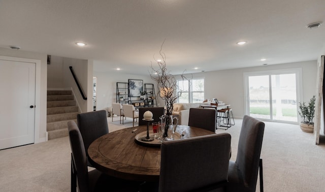 dining space featuring recessed lighting, light colored carpet, and stairs