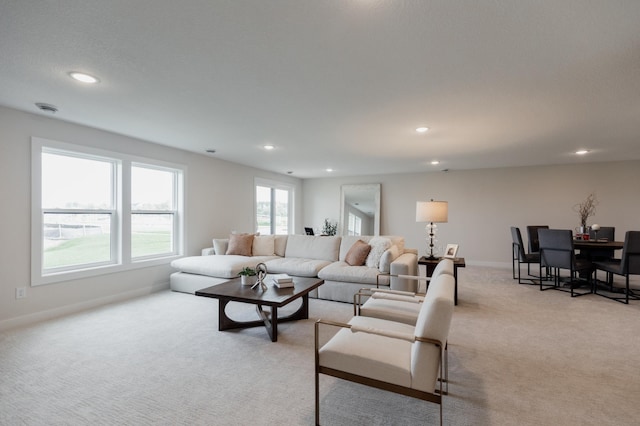 living room with recessed lighting, light colored carpet, and baseboards