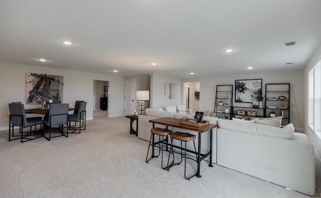 living area featuring baseboards, recessed lighting, and light colored carpet