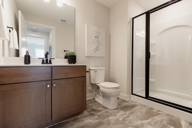 full bath featuring toilet, a stall shower, vanity, and baseboards