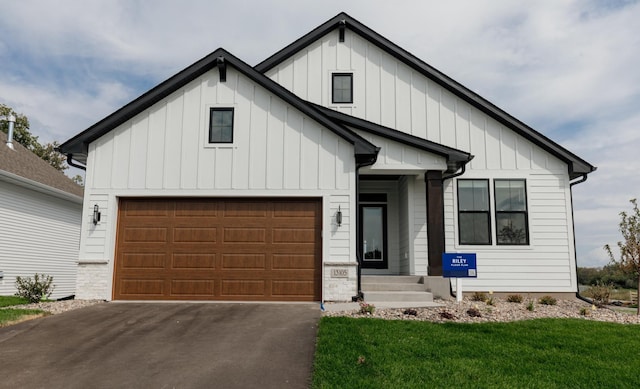 modern inspired farmhouse with driveway, board and batten siding, stone siding, and a front lawn