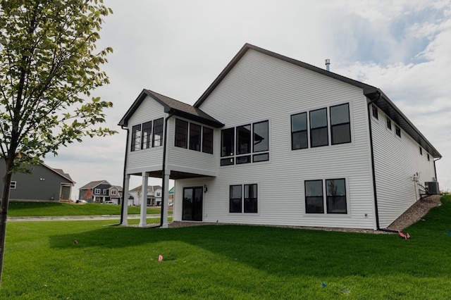 back of property featuring central AC, a sunroom, and a lawn