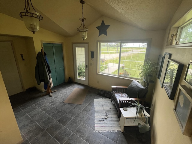 doorway with a textured ceiling and lofted ceiling