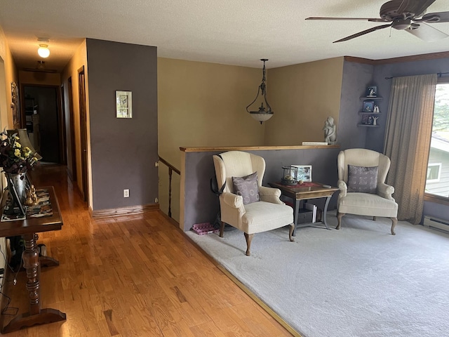 living area featuring hardwood / wood-style flooring, a textured ceiling, and ceiling fan