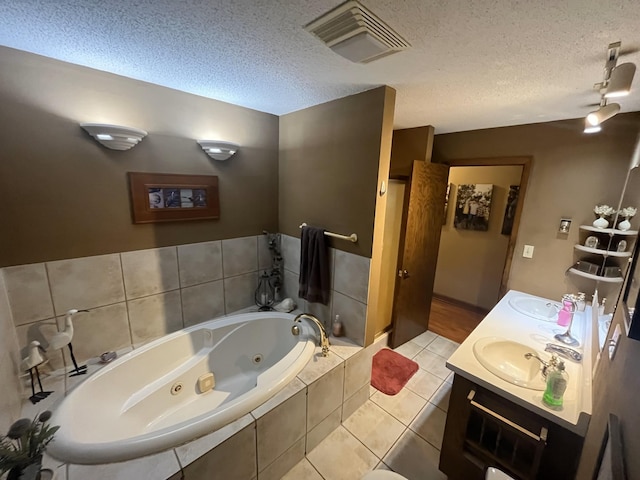 bathroom featuring a textured ceiling, tile patterned flooring, tiled tub, and vanity