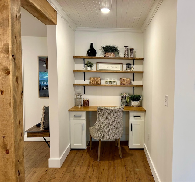 home office featuring dark wood-type flooring, crown molding, and built in desk